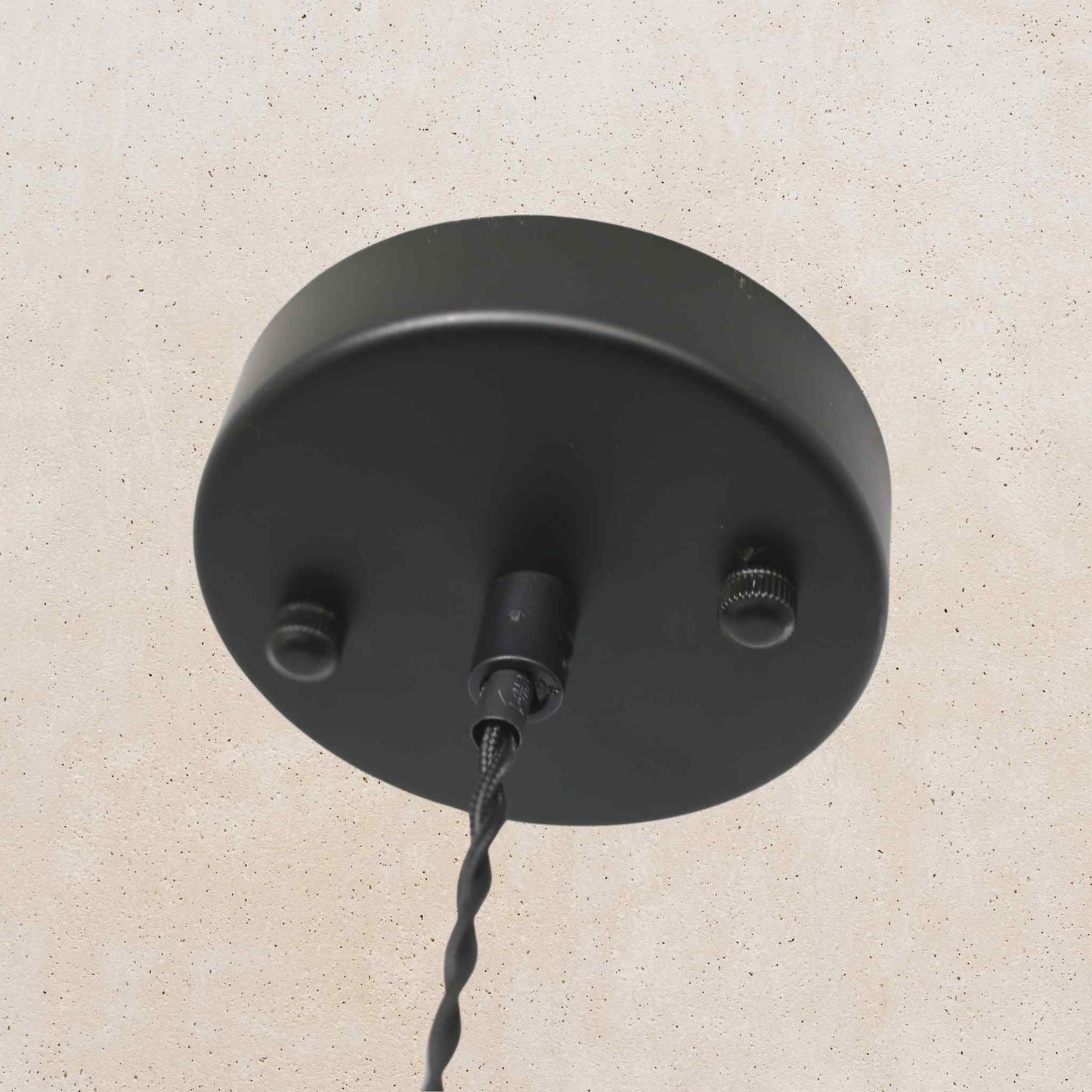 Black ceiling light fixture on a beige wall