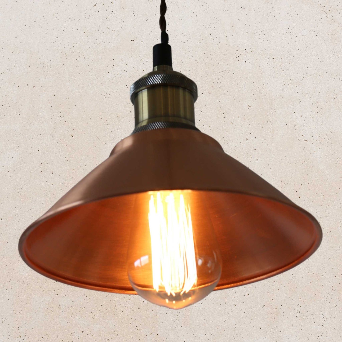 Vintage-style copper pendant light with a lit bulb on a beige background