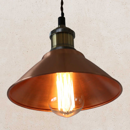 Vintage-style copper pendant light with a lit bulb on a beige background