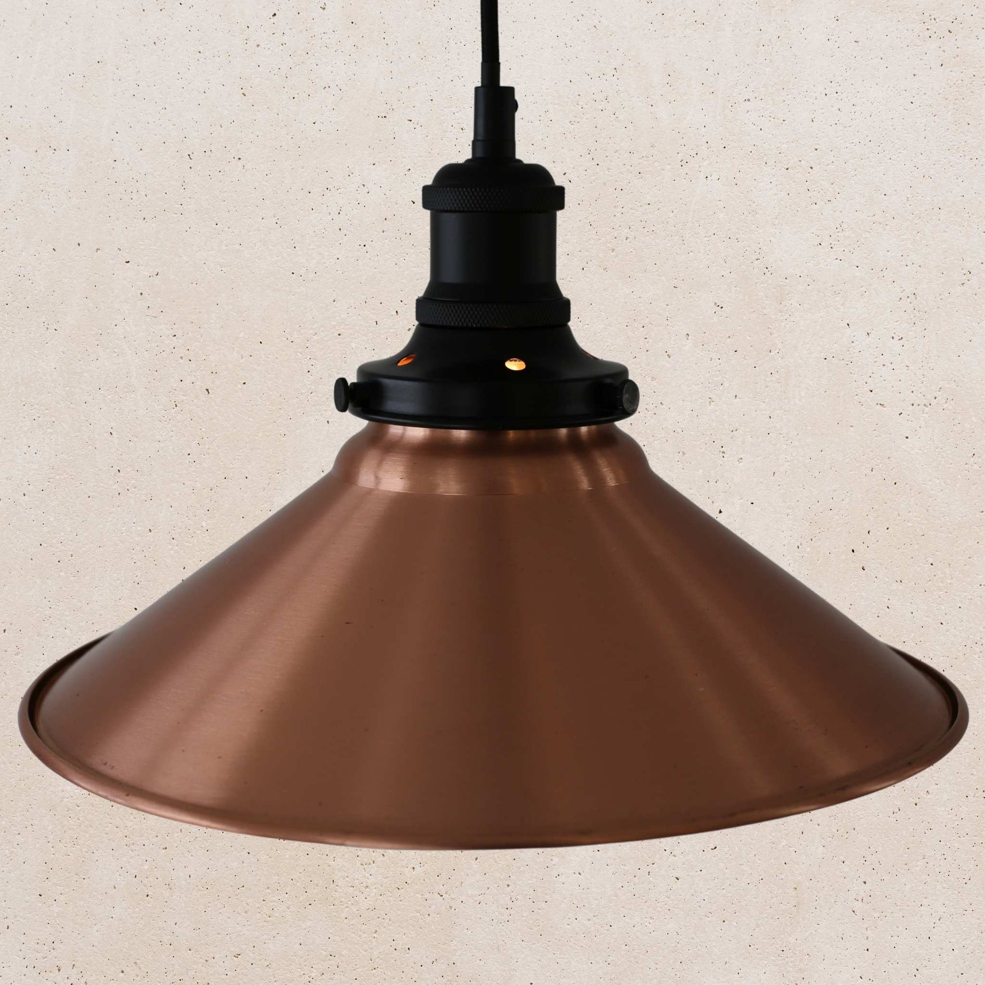Copper pendant light against a beige textured wall
