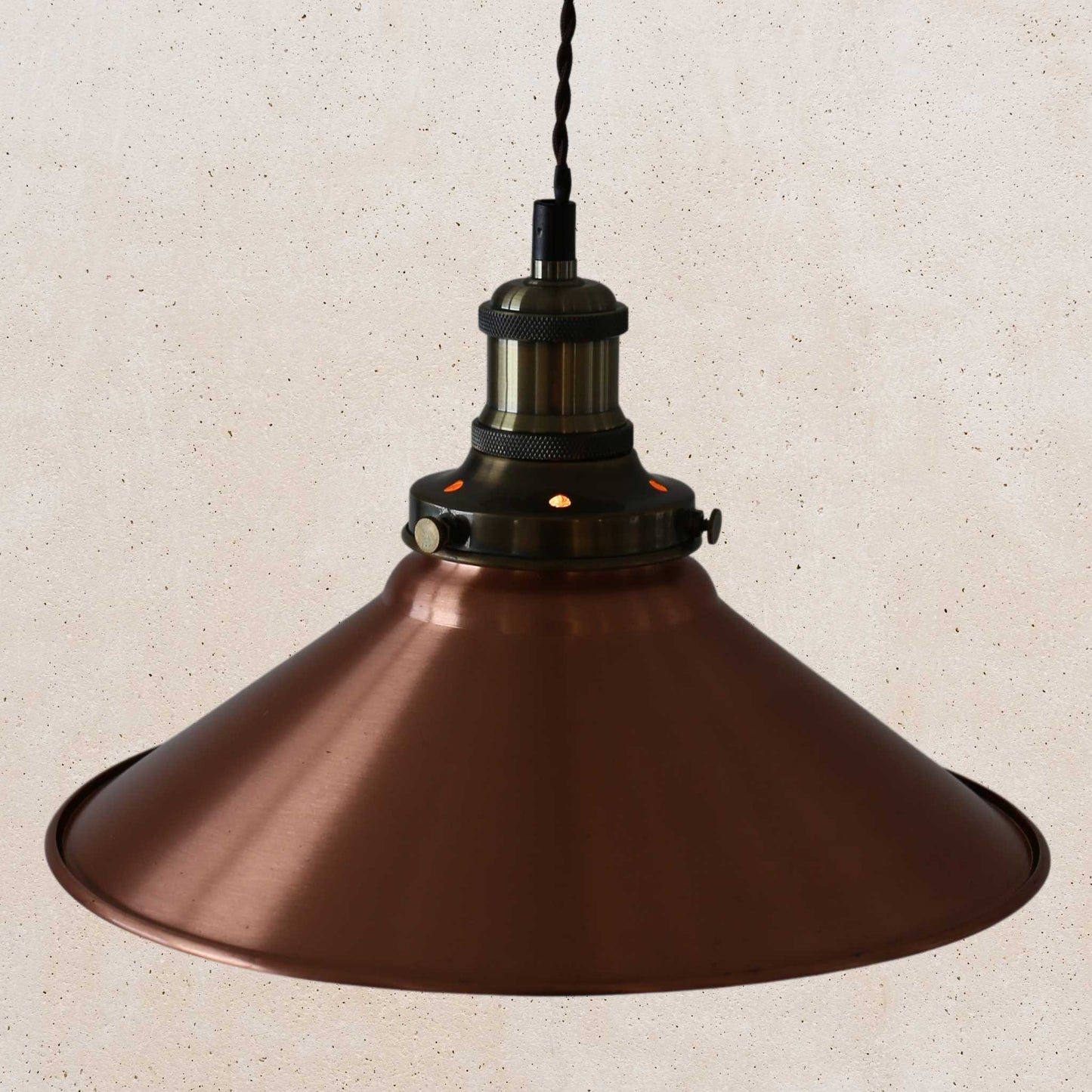 Copper pendant light against a beige textured wall
