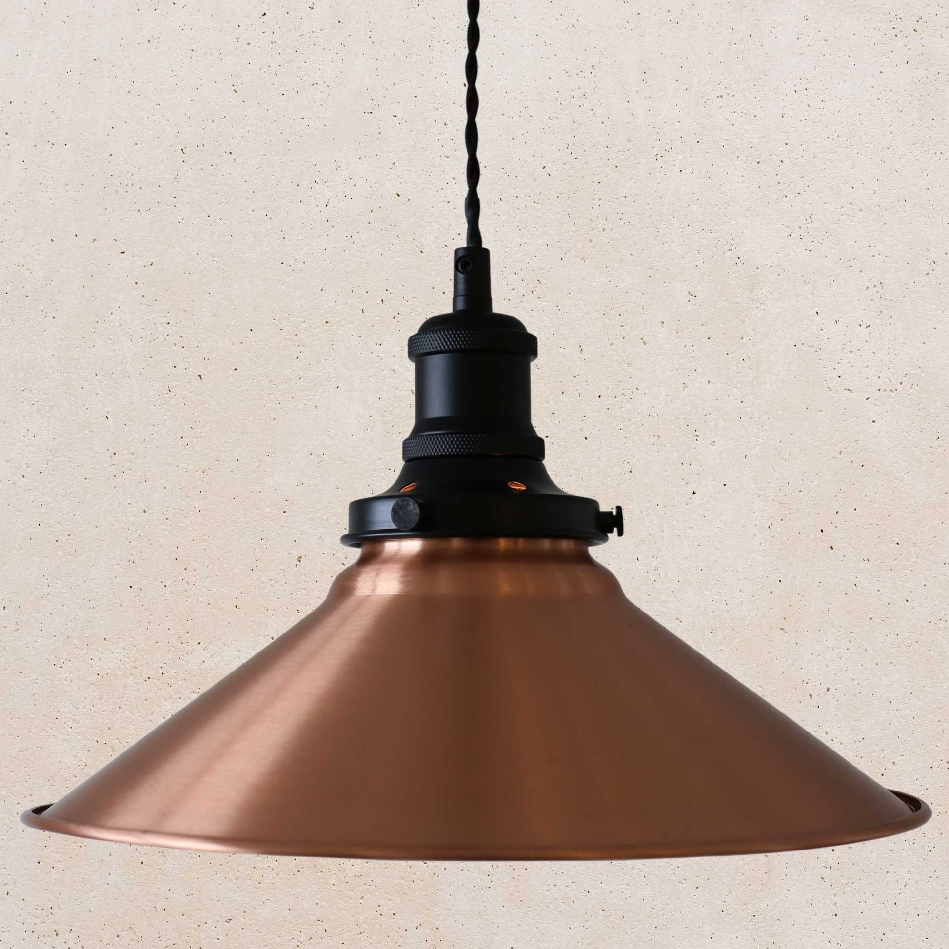 Copper pendant light with black fixture on a beige background
