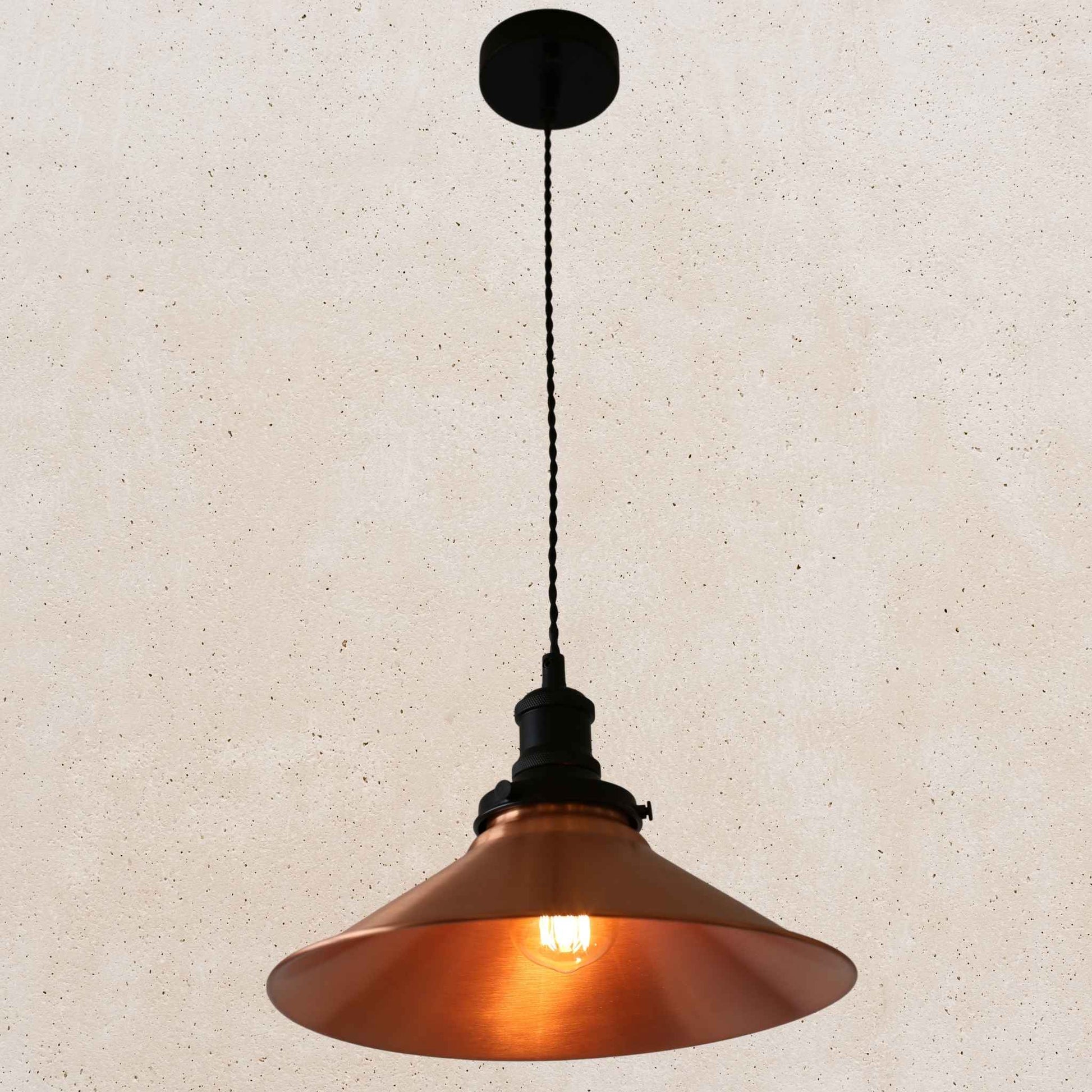 Copper pendant light with black fixture on a beige background