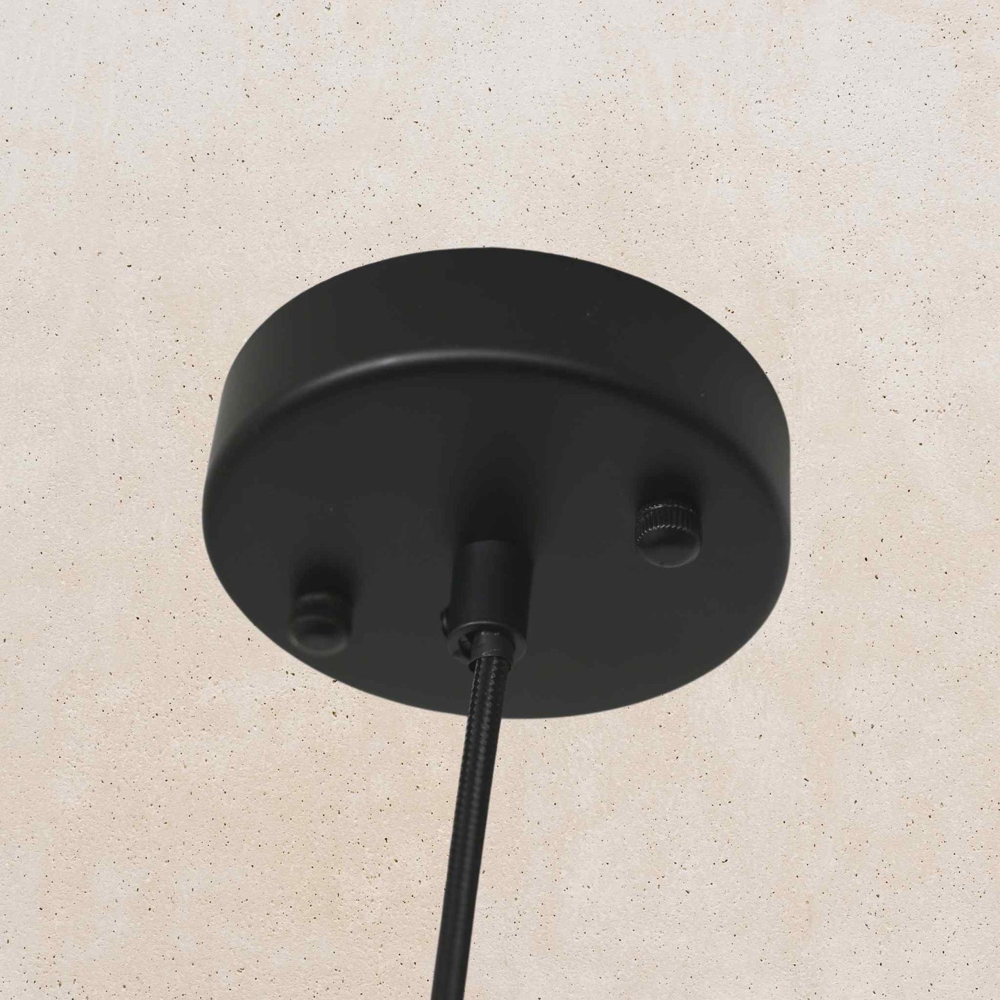 Black ceiling light fixture on a beige wall