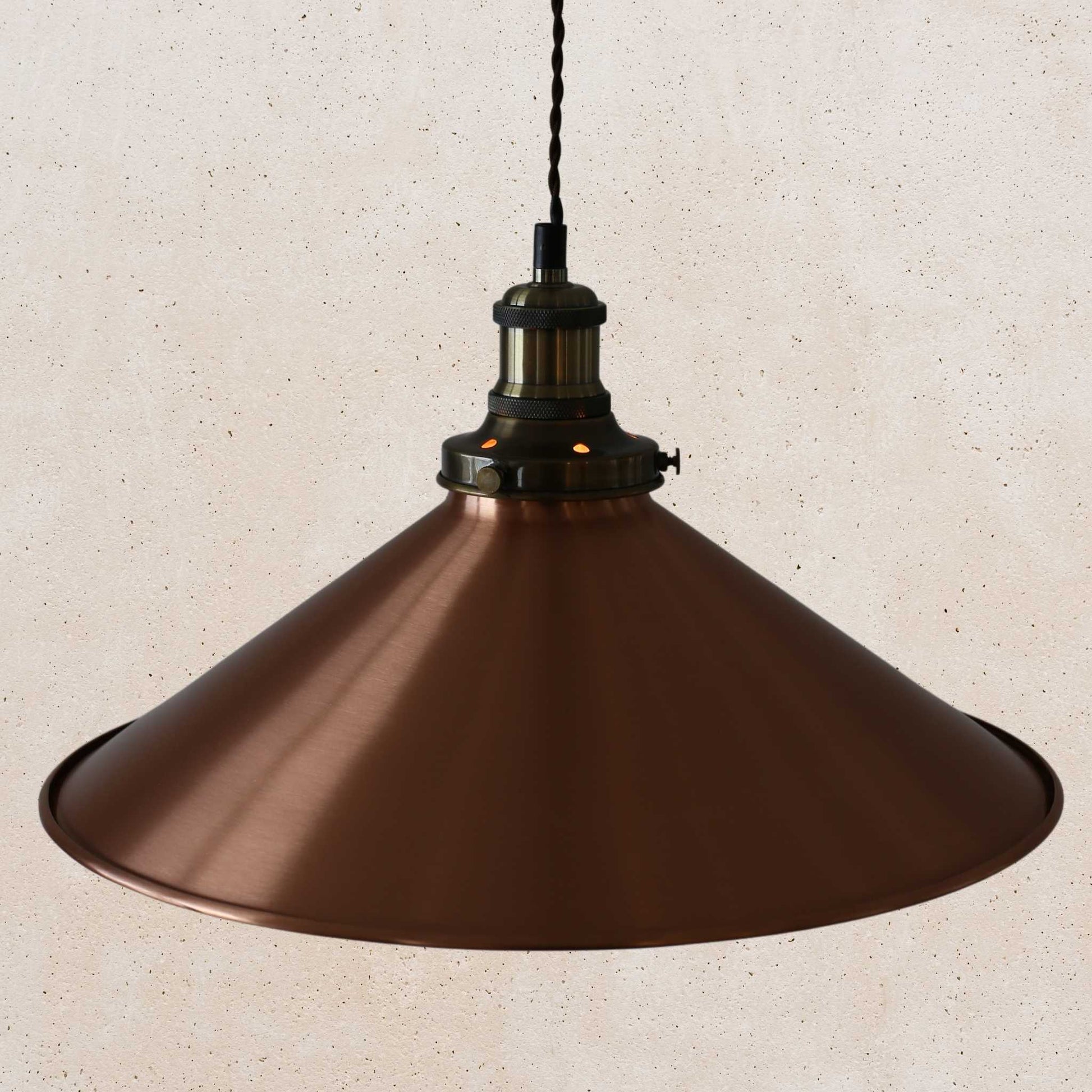 Copper pendant light against a beige wall