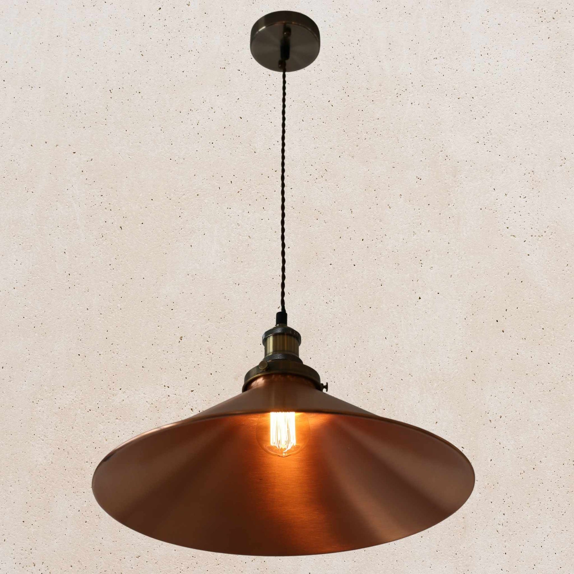 Copper pendant light against a beige wall