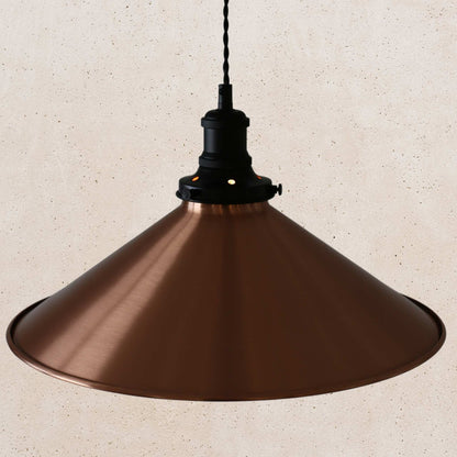 Copper pendant light against a beige wall
