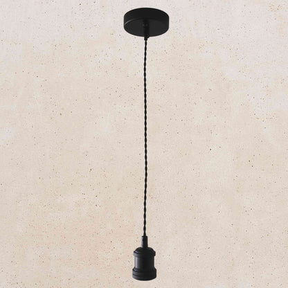 Black pendant light with a cord on a beige background