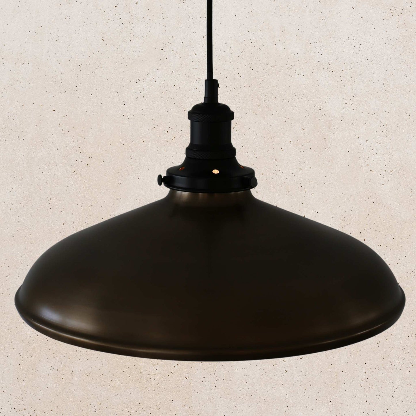 Antique brass pendant light on a beige speckled background