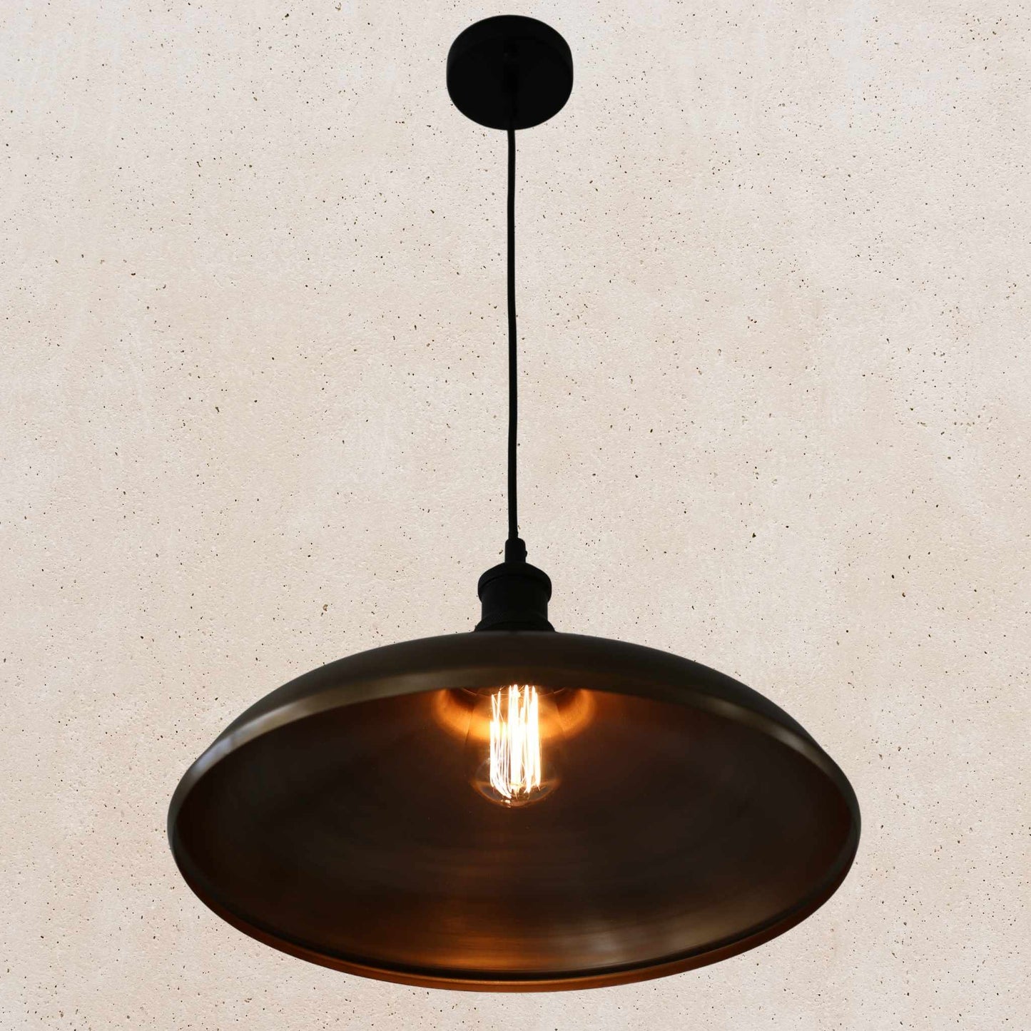 Antique brass pendant light on a beige speckled background