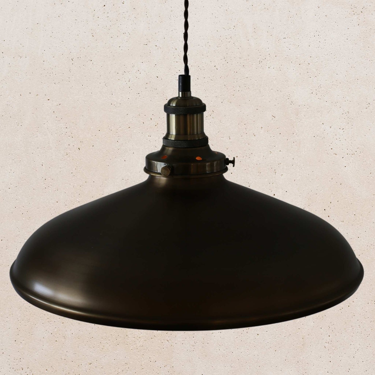 Antique brass pendant light on a beige speckled background