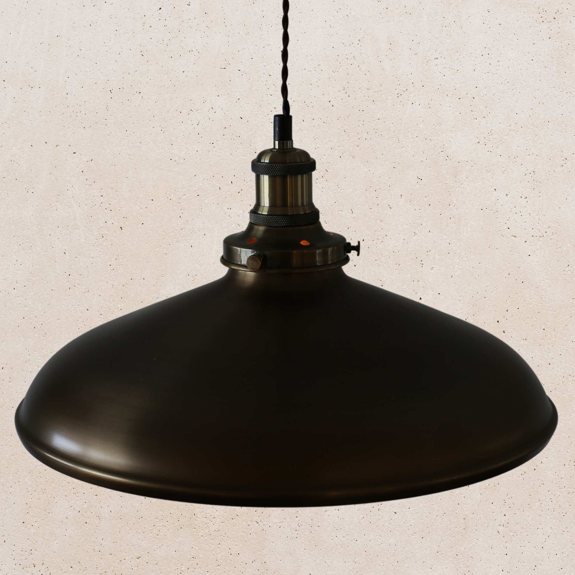 Antique brass pendant light on a beige speckled background