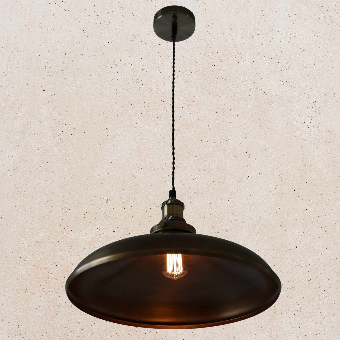 Antique brass pendant light on a beige speckled background
