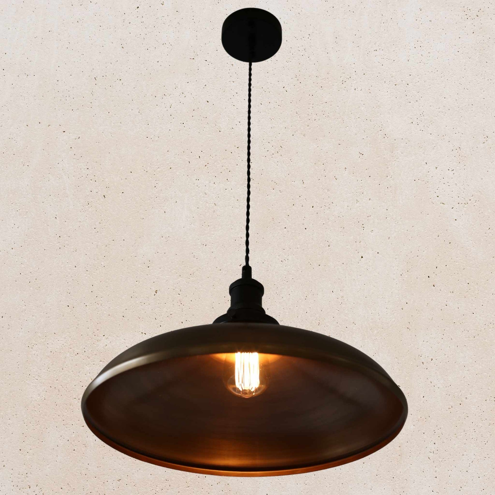 Antique brass pendant light on a beige speckled background