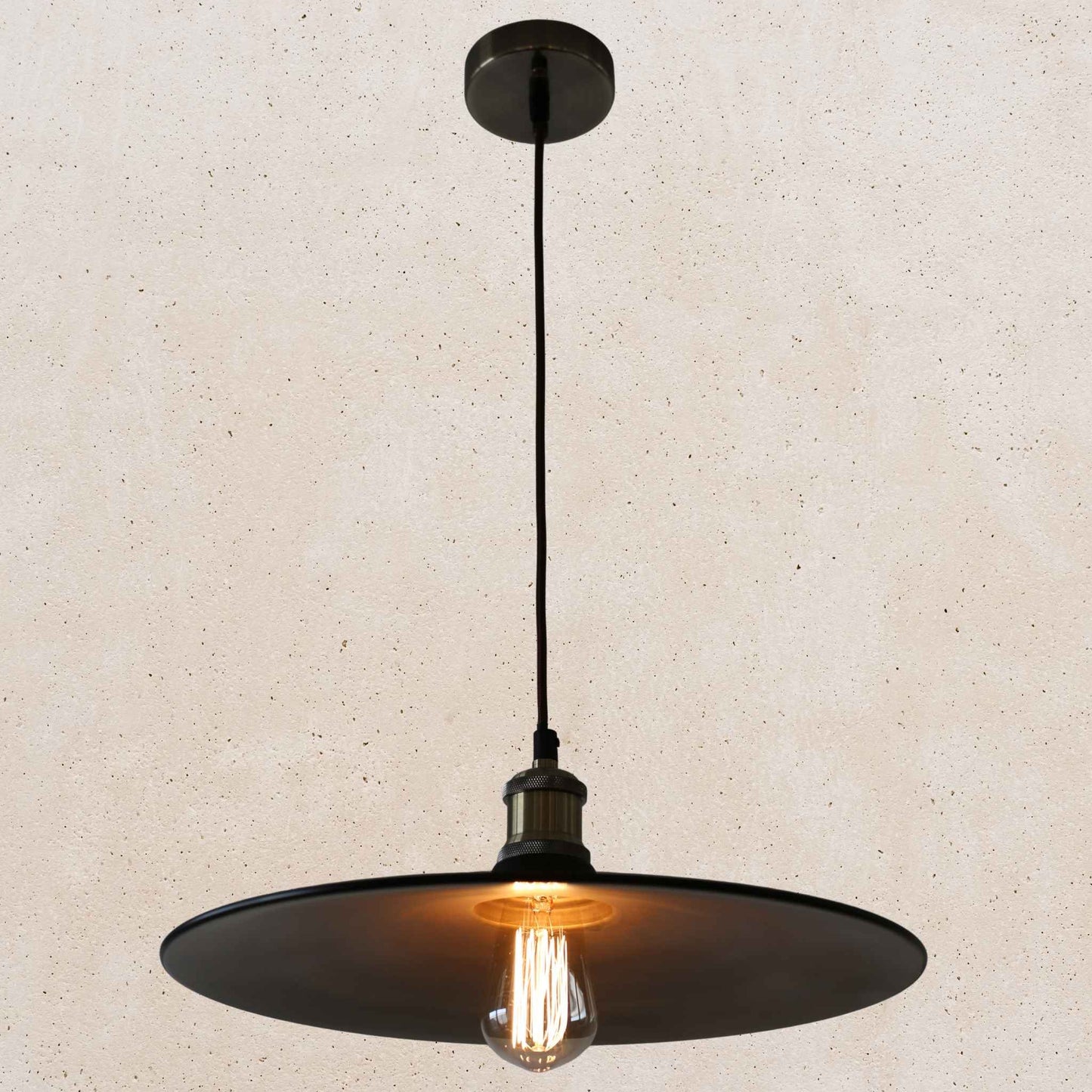 Black pendant light with a lit bulb on a beige background