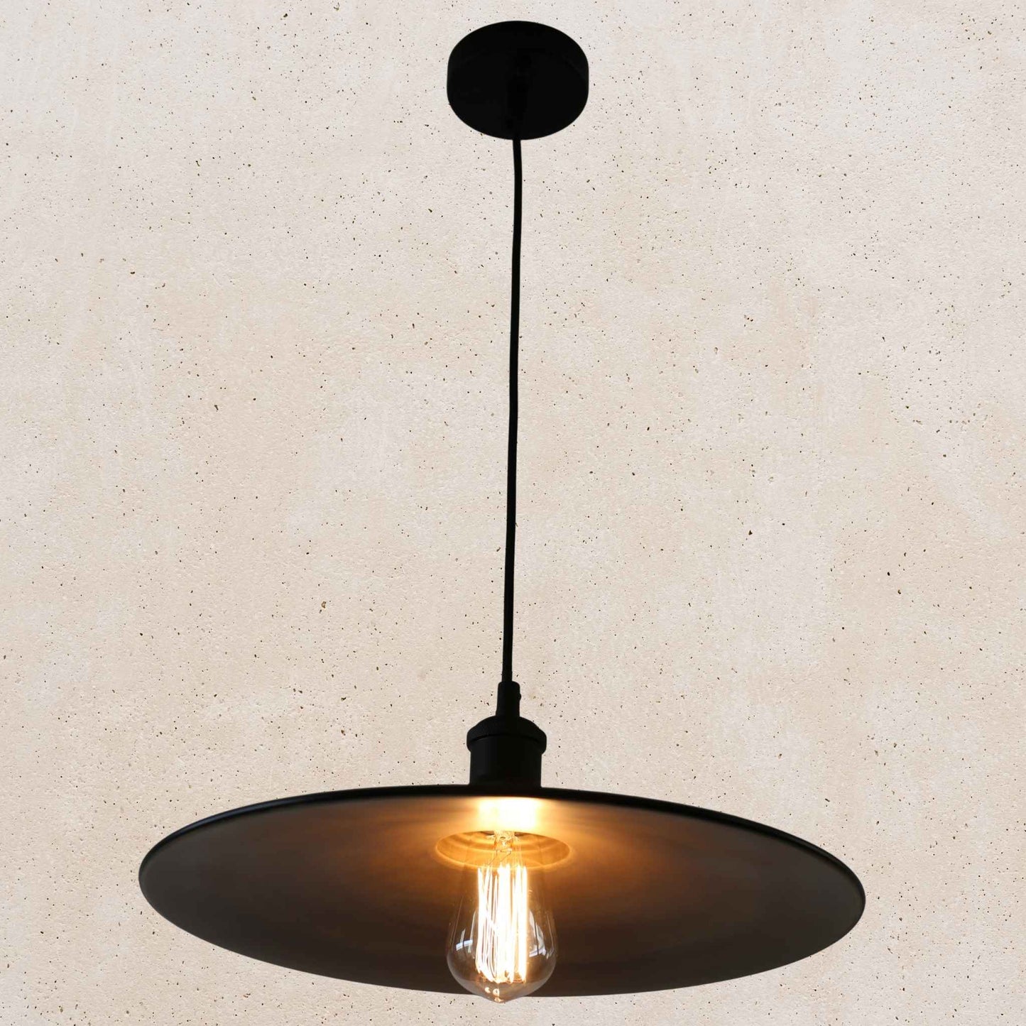 Black pendant light with a lit bulb on a beige background