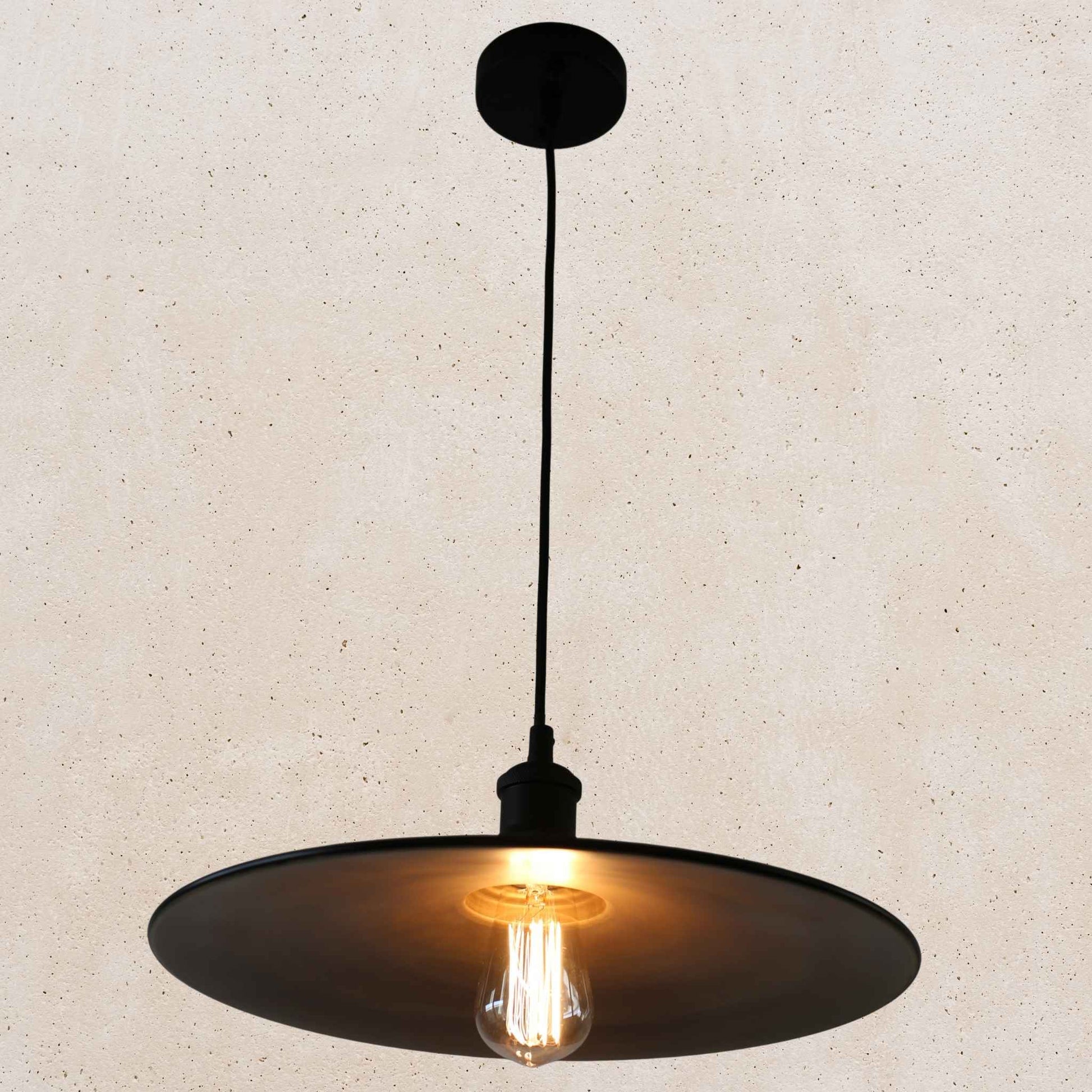 Black pendant light with a lit bulb on a beige background