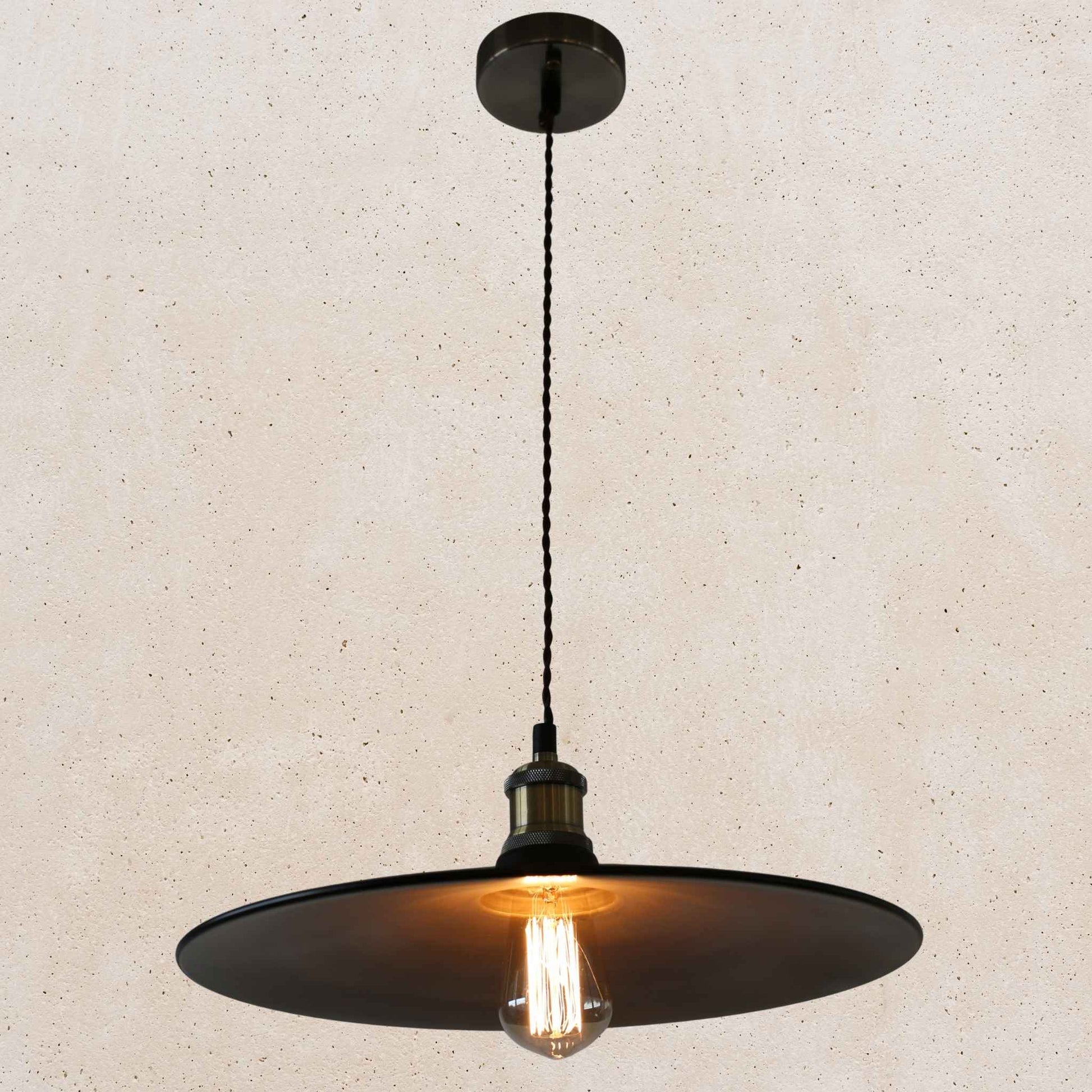 Black pendant light with a visible bulb on a beige background