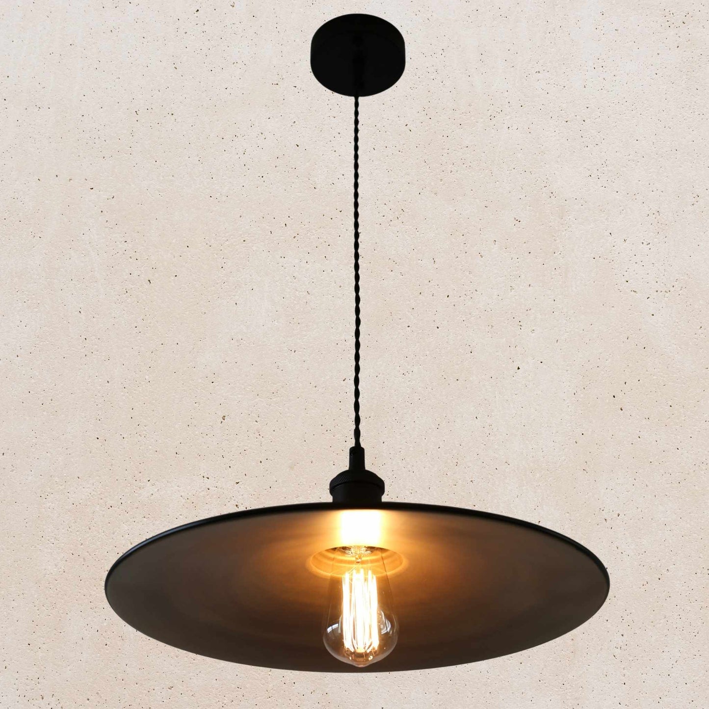Pendant light with a black shade and exposed bulb on a beige background