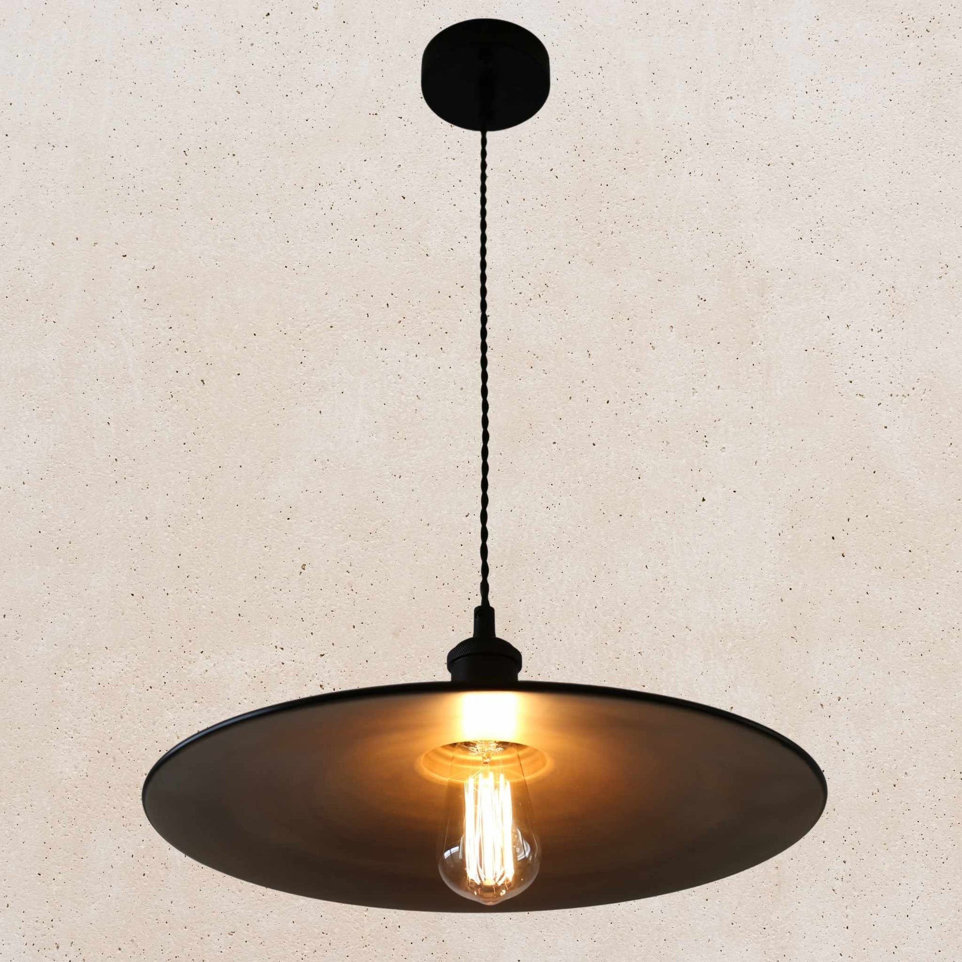 Pendant light with a black shade and exposed bulb on a beige background
