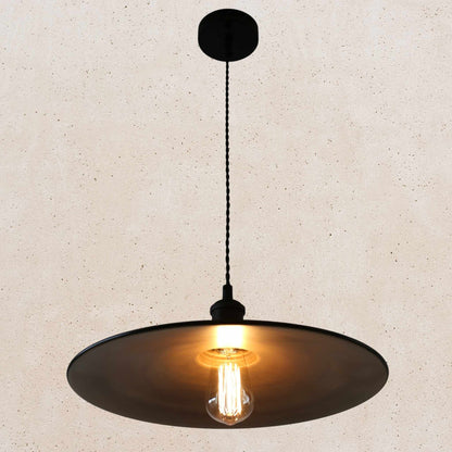 Pendant light with a black shade and exposed bulb on a beige background